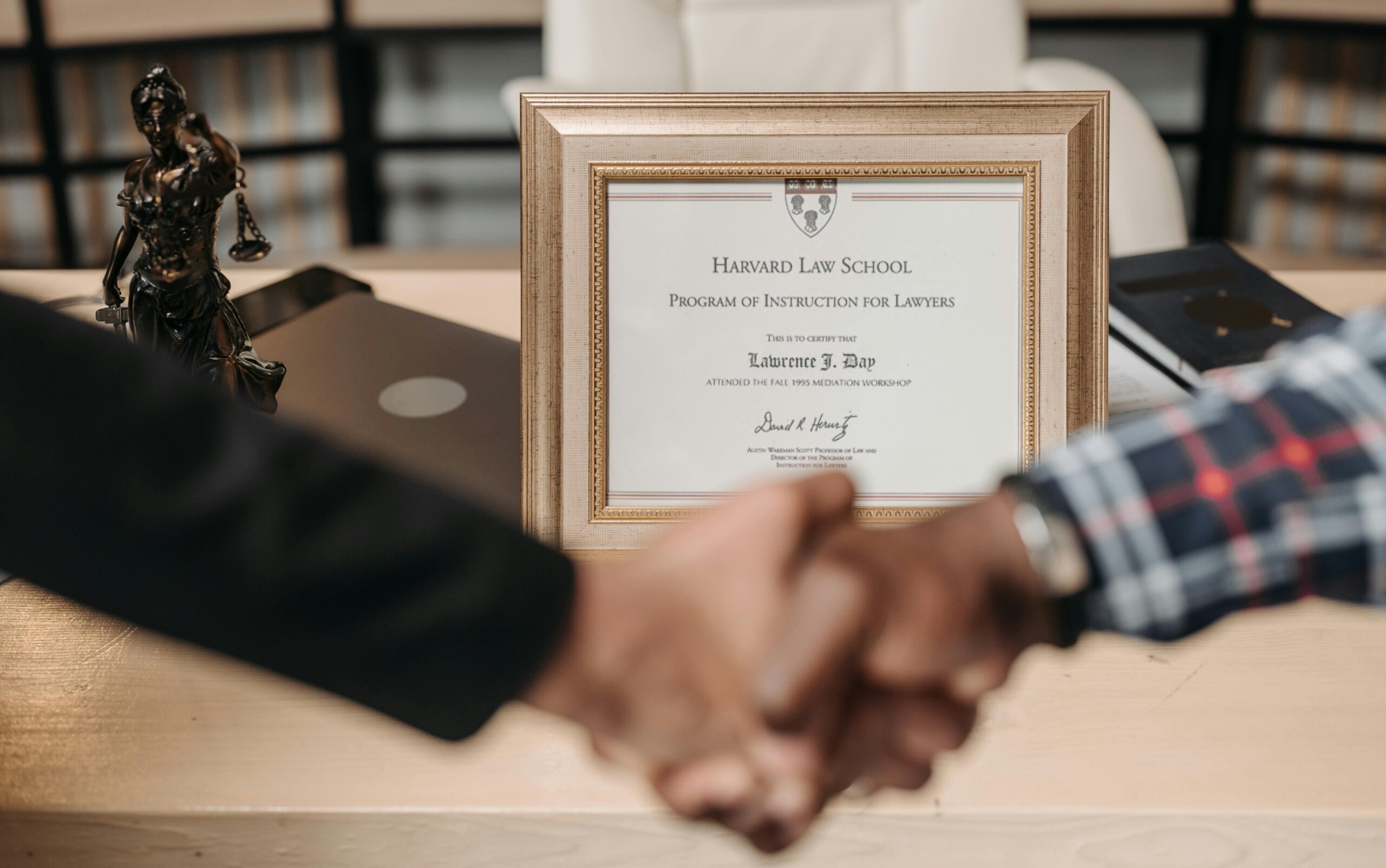 Harvard Law School degree with handshake representing achievement and professional agreement.