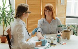 Doctor measuring patient's blood pressure with digital monitor in a clinical setting.